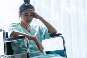 a person in a wheelchair holds their head while struggling with traumatic brain injury and addiction