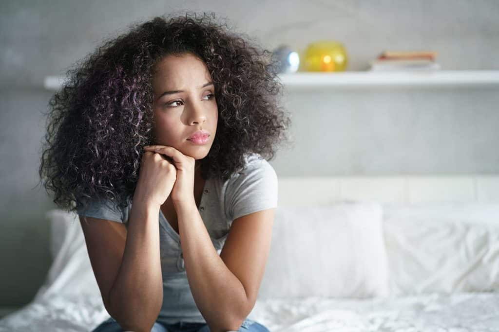 a person sits on a bed possibly struggling with depression and addiction