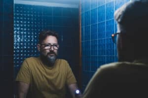 a person looks sadly in a mirror thinking of the most commonly abuse prescription medications