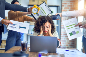 a person at a computer with other people reaching over them struggles withstaying sober during stress