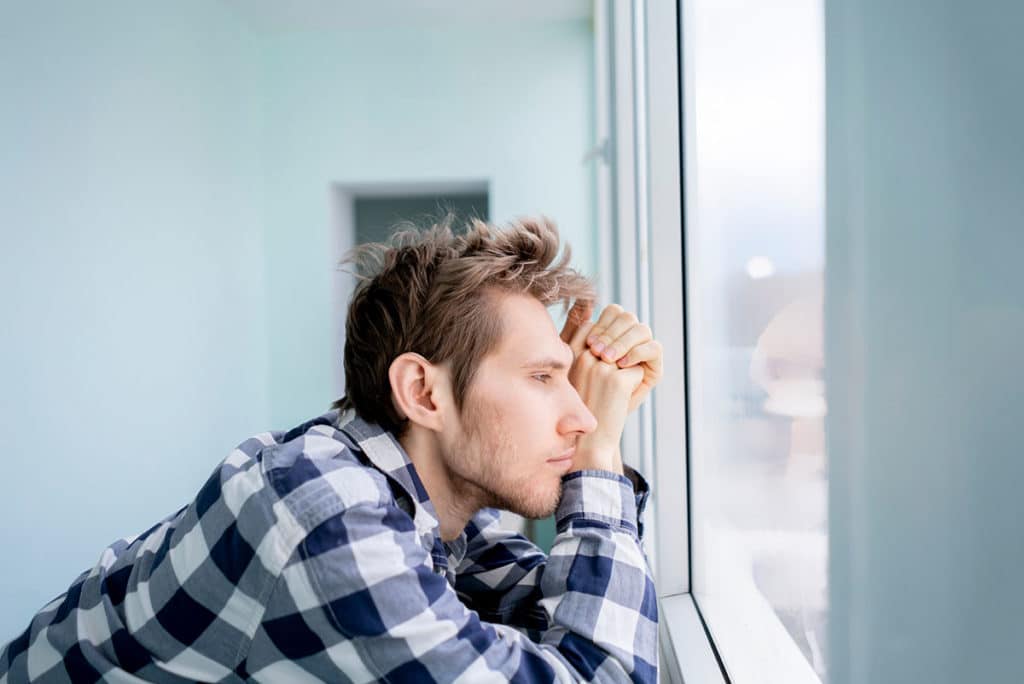 a person looks anxiously out of a window possibly struggling to understand buspar abuse