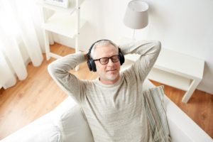 a man leans back in a chair listening to music with headphones