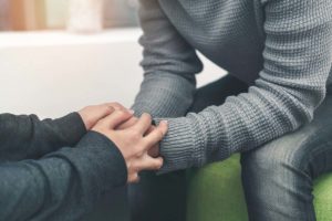 a person holds another's hands during Alcohol Abuse Treatment