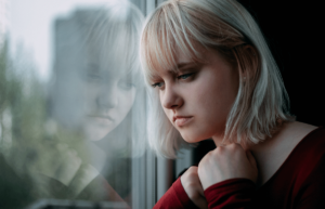 a person looks out of a gloomy window wondering if they can make a schizophrenia recovery