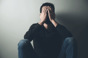 a person sits on the floor with their hands on their face as they experience the side effects of fentanyl