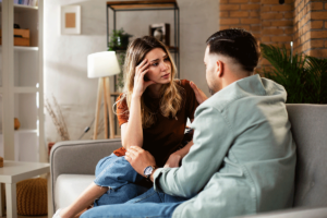 two concerned people sitting on couch while discussing signs of xanax use in a friend