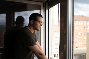 pensive person looking out window while considering signs its time for drug addiction treatment