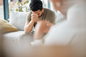 person in therapy with head hanging against hands learning how cognitive behavioral therapy can help ptsd