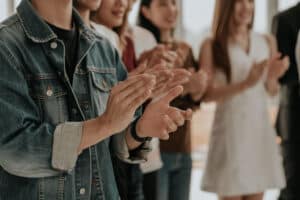 people in group therapy clapping to support each other while making amends during addiction recovery